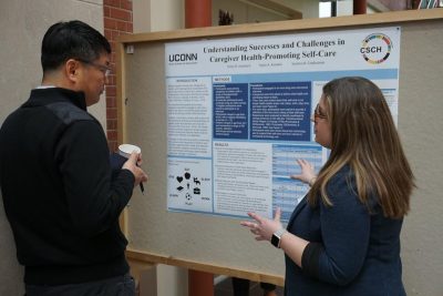 Two students discuss a research poster at the symposium.